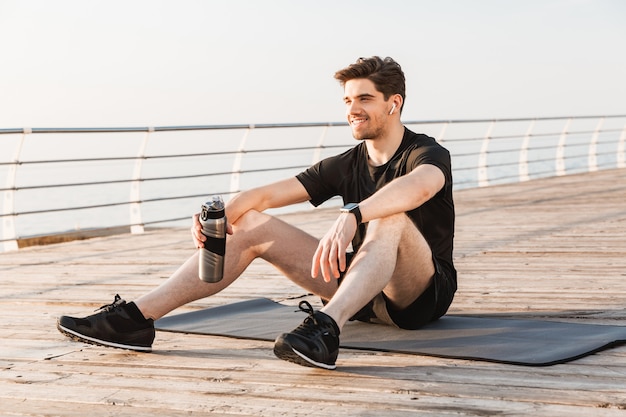 Handsome young sportsman listening music with earphones.