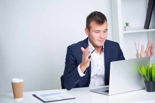 Handsome young worker working in a company office with documents and a laptop