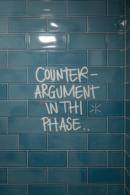 Photo handwritten counterargument on tiled wall indoors