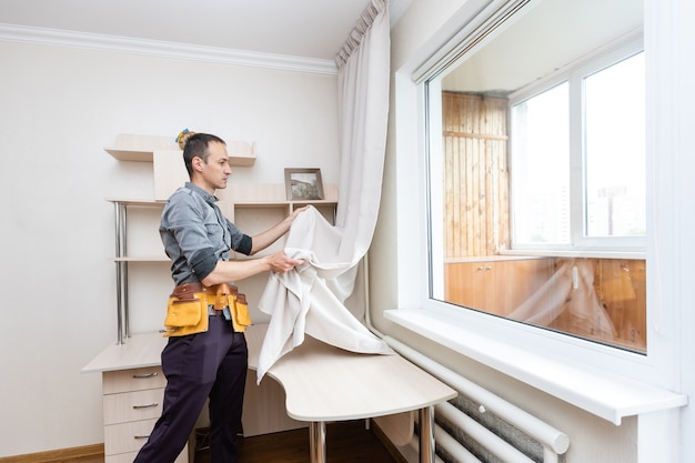 A handyman installing new cornice for curtains, home repair and renovation works.