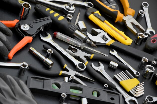 Handyman tool kit on black wooden table Many wrenches and screwdrivers pilers and other tools for any types of repair or construction works Repairman tools