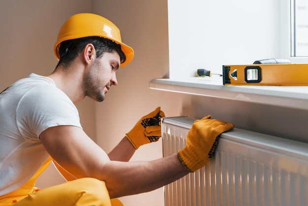 Handyman in yellow uniform installing new battery House renovation conception