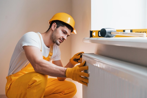 Handyman in yellow uniform installing new battery House renovation conception