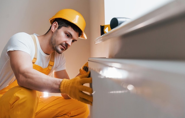 Handyman in yellow uniform installing new battery House renovation conception