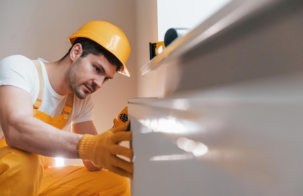 Handyman in yellow uniform installing new battery House renovation conception