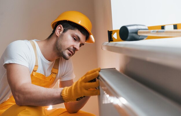 Handyman in yellow uniform installing new battery House renovation conception