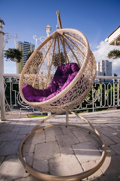 hanging chair cocoon with a purple cushion on the summer terrace of the restaurant