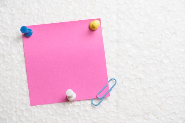 Hanging from wall with help stationery buttons is pink sticker for notes