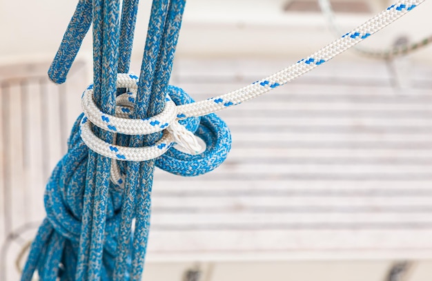 Photo hanging nautical ropes tied in a knot on a blurred background of the deck of a yacht