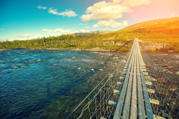 Hanging rope wooden bridge over the mountain river