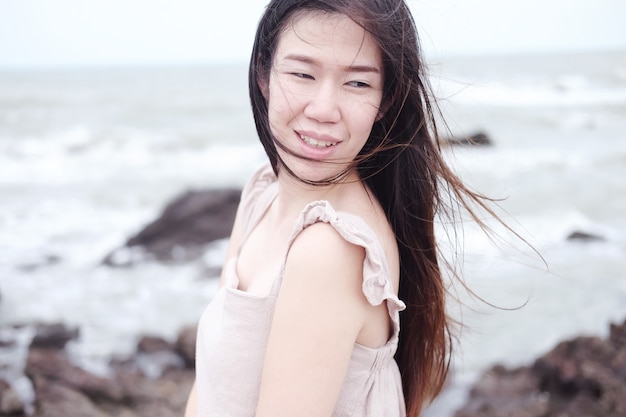 Happiness of asian woman is standing on wooden bridge Extending into the sea on Holiday. She is smiling in the natural wind and sea on vacation and summertime in Thailand