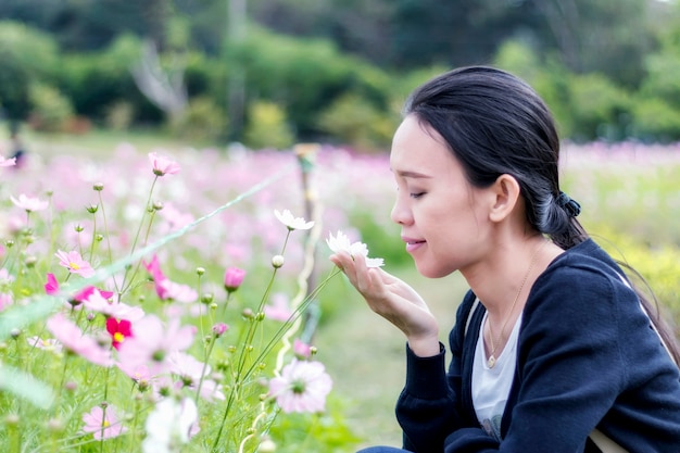 Happiness asian woman touch and smell cosmos flower in park