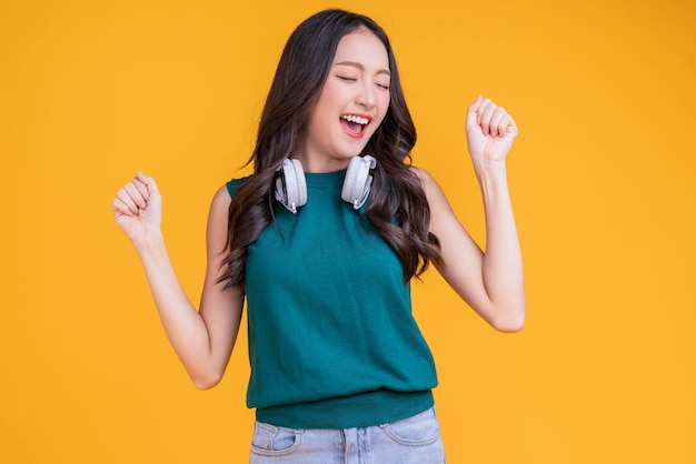 Happiness carefree asian female woman teen wearing headphone listen dance joyful fun moving moment teen wear casaul cloth singing move while laugh smile trendy lifestyle studio shot