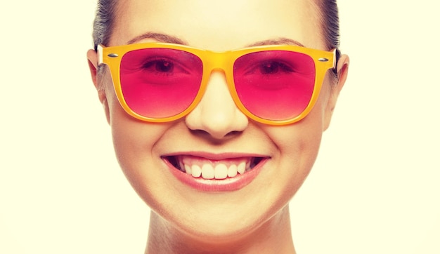 happiness, face expressions and people concept - portrait of smiling teenage girl in pink sunglasses