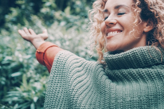 Happiness and freedom emotions with close up portrait of excited woman opening arms and smiling with closed eyes Healthy and joyful life people in nature with green in background Female enjoy park