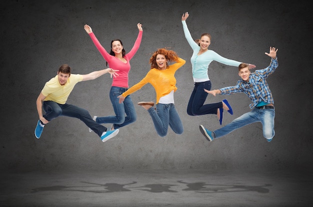 happiness, freedom, friendship, education and people concept - group of smiling teenagers jumping in air over green board background