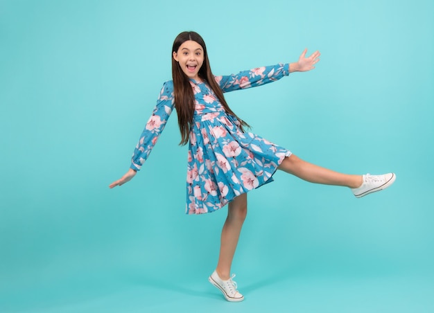 Happiness freedom motion and child Young teenager girl jumping over blue background funny jump Excited teenager amazed and cheerful emotions