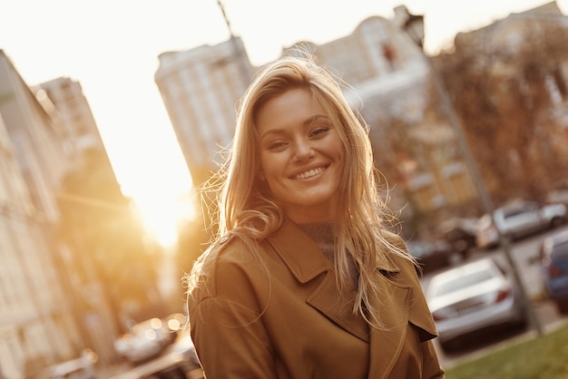 Happiness highlights her beauty. Attractive young smiling woman looking at camera while standing outdoors