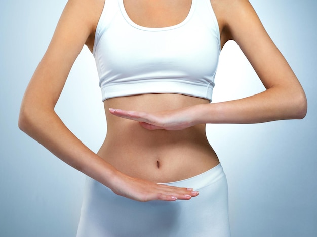 Happiness is a healthy body Shot of an unidentifiable young woman posing with her hands over her stomach in the studio