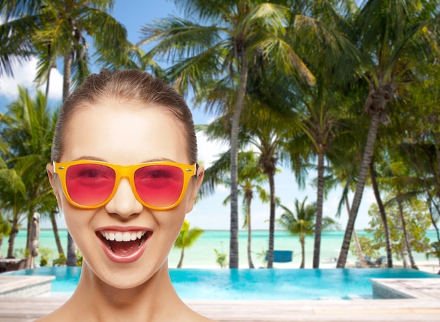 happiness and people concept - portrait of happy teenage girl in pink sunglasses