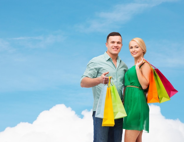 happiness, shopping and couple concept - smiling couple with shopping bags