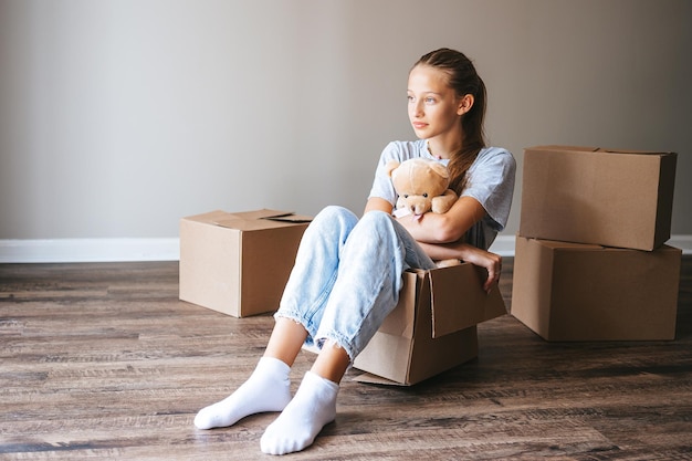 Happy adorable girl with cardboard boxes in new house at moving day