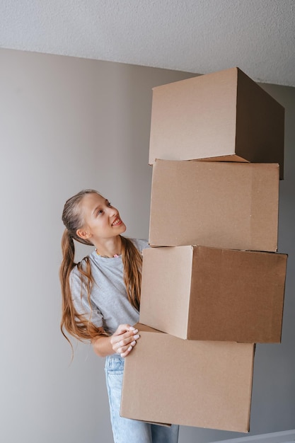 Happy adorable girl with cardboard boxes in new house at moving day