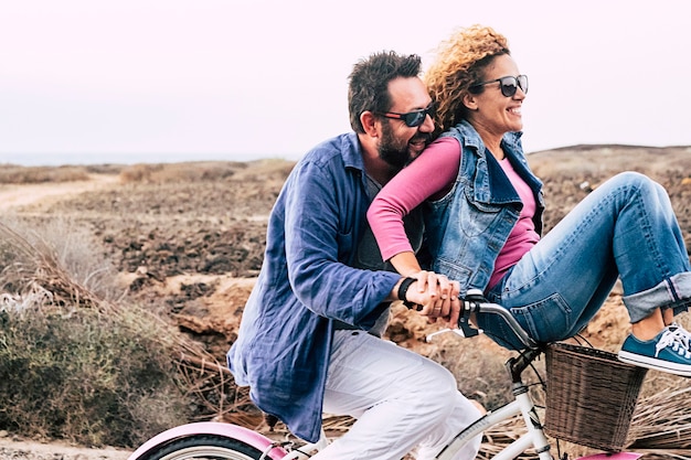 Happy adult caucasian couple having fun with bicycle in outdoor leisure activity active people