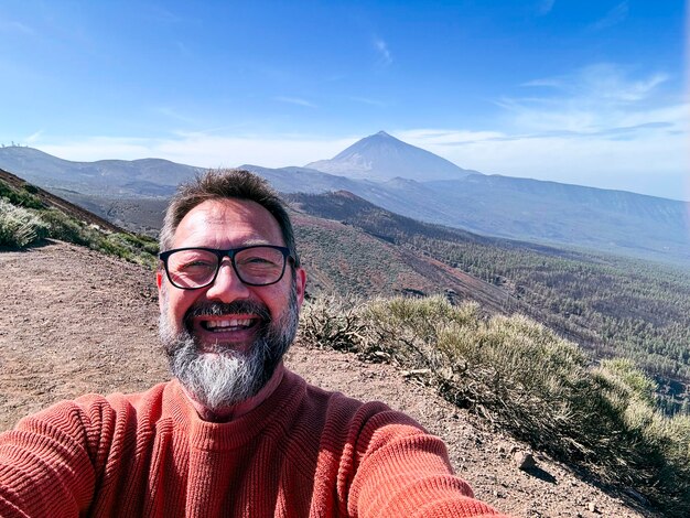 Photo happy adult man traveler taking selfie picture with scenic view on background from high point of vew travel and happiness concept lifestyle one joyful mature male using phone in outdoor leisure