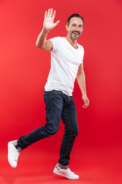 Happy adult man walking isolated waving.