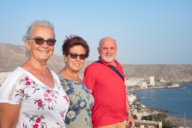 Happy adult mature senior friends enjoying the scenery from the hill enjoying vacation and good time