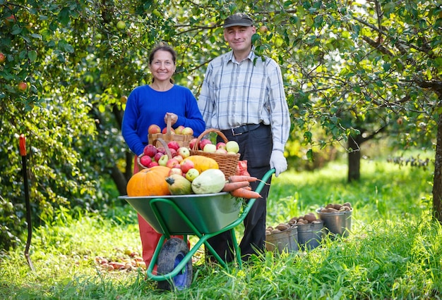 Happy adult men and women with a great harvest in the outdoor garden