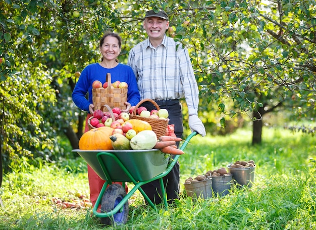 Happy adult men and women with a great harvest in the outdoor garden