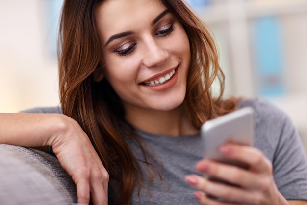 happy adult woman using phone at home in the living room