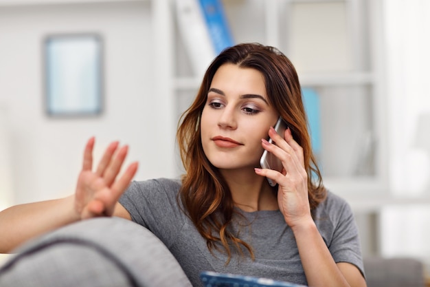 happy adult woman using phone at home in the living room