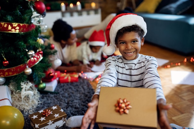 Happy African American boy holding Christmas present and looking at camera