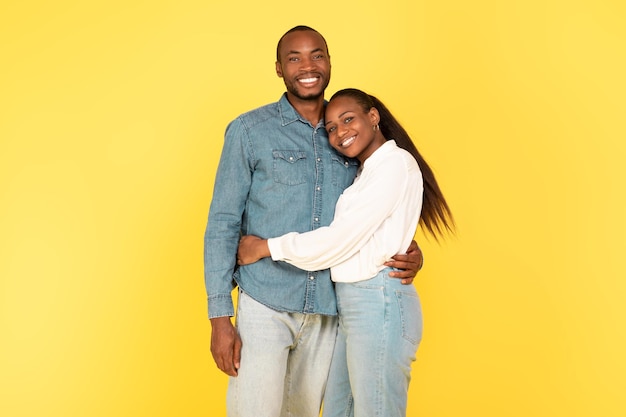 Happy African American Couple Hugging Posing On Yellow Background