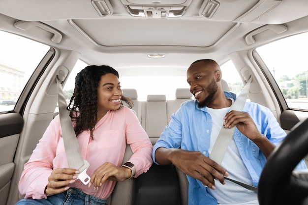 Happy african american couple putting on seatbelts