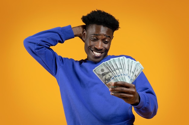 Happy african american guy looking at cash in his hand