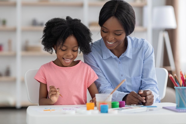 Happy african american kid enjoying painting at kindergarten