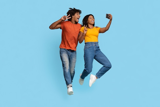 Happy african american lovers taking selfie together on blue