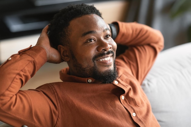 Happy African American Man Relaxing Sitting On Sofa At Home