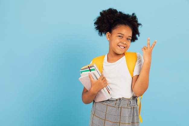 Happy African American schoolgirl pointing cool on blue background back to school concept