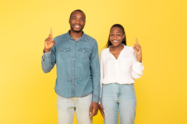 Happy African American Spouses Pointing Fingers Up Over Yellow Background