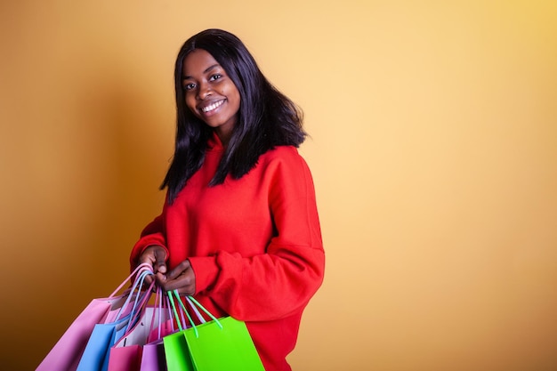 Happy African American woman in a red hoodie with colorful shopping bags