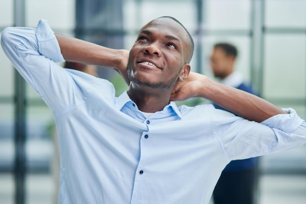 Happy african american young businessman holding his hands behind his head