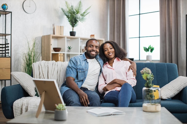 Happy african couple sitting on couch in embrace