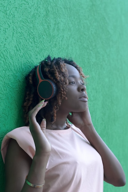 A happy AfricanAmerican woman is listening to music with headphones Entertainment and recreation