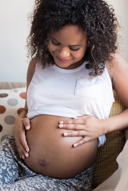 Happy afro woman showing her pregnant belly