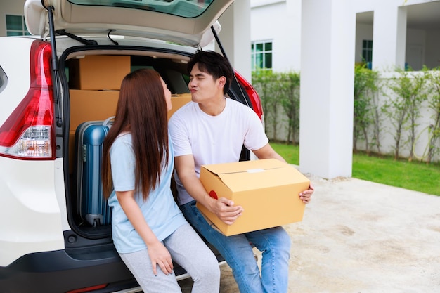 Happy aisan couple help moving cardbord boxes to new house together Moving day